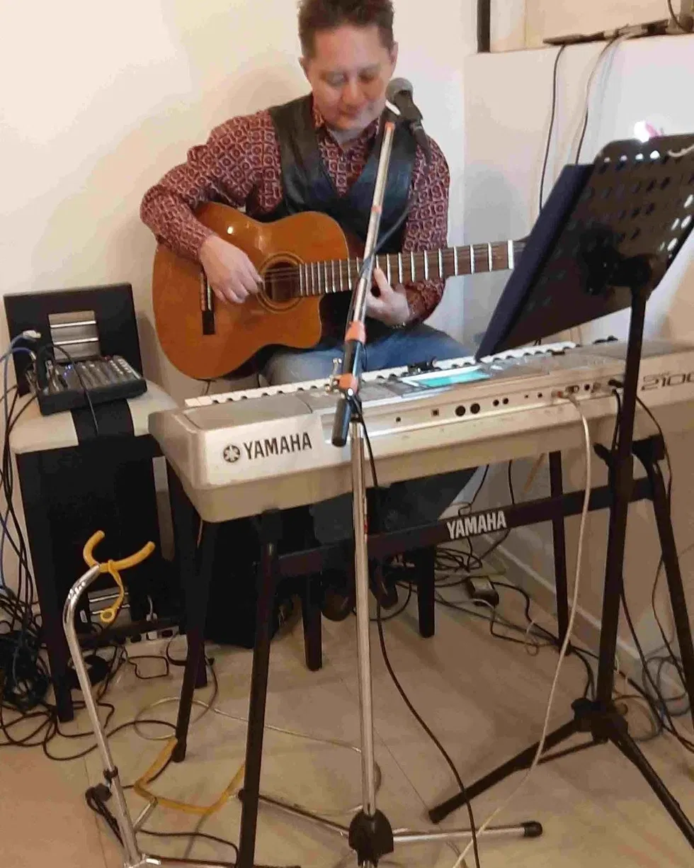 Roberth Tamayo tocando guitarra sentado junto al teclado